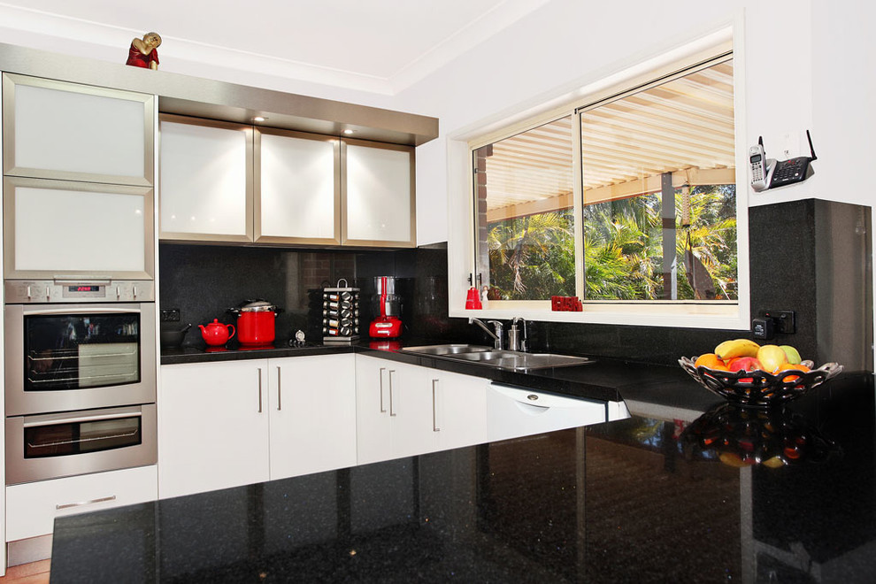 Inspiration for a mid-sized transitional u-shaped enclosed kitchen remodel in DC Metro with a double-bowl sink, flat-panel cabinets, white cabinets, granite countertops, black backsplash, stone slab backsplash, stainless steel appliances and a peninsula
