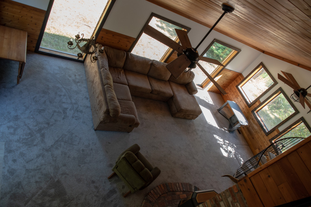 Mid-sized country loft-style living room in Seattle with carpet, a wood stove, multi-coloured floor and timber.