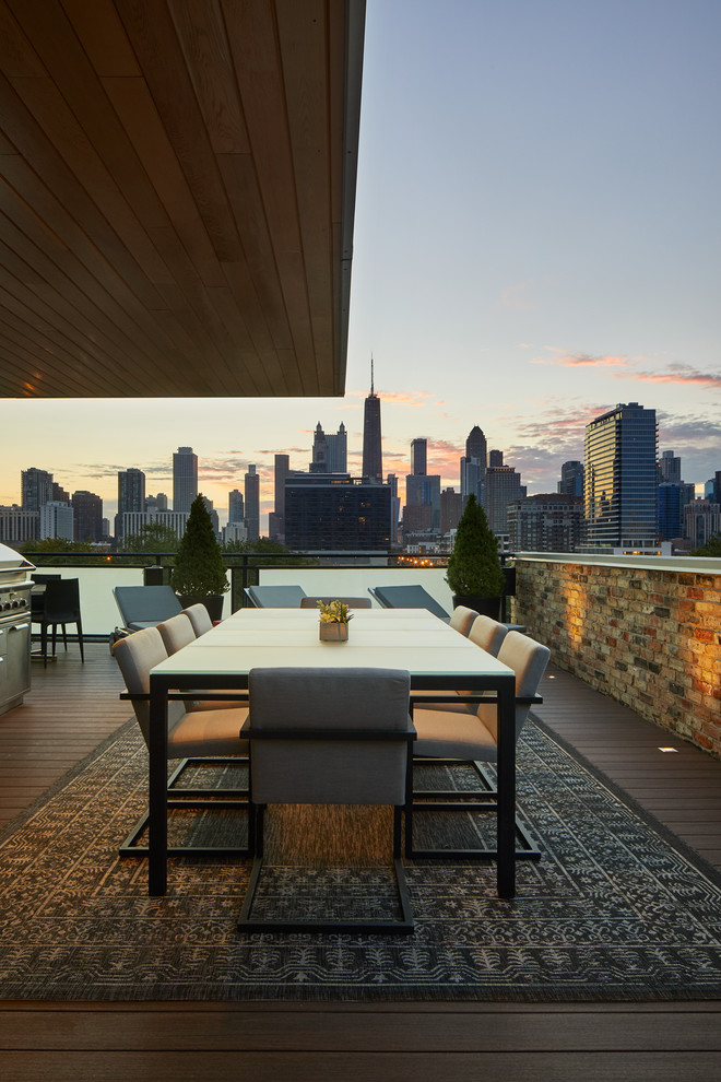 Photo of a mid-sized modern rooftop deck in Chicago with a fire feature and an awning.