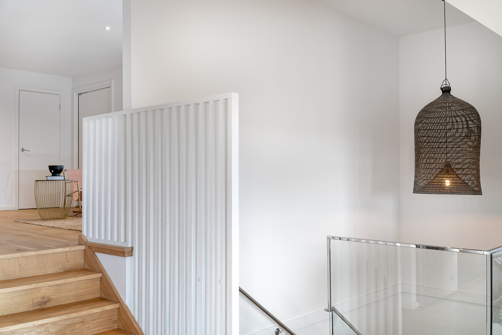 This is an example of a mid-sized contemporary hallway in Melbourne with white walls, bamboo floors and brown floor.