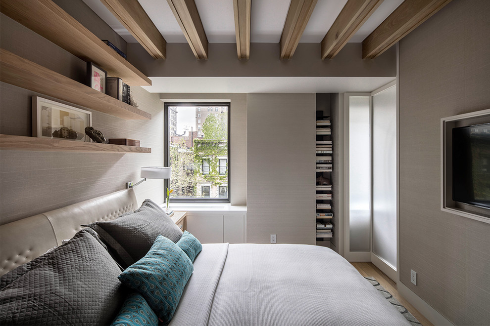 This is an example of a small contemporary master bedroom in New York with beige walls and light hardwood floors.