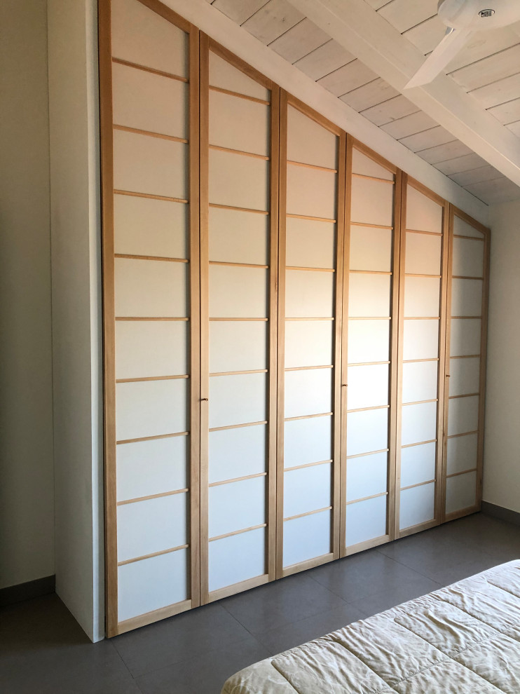 This is an example of a large asian gender-neutral built-in wardrobe in Bologna with light wood cabinets.