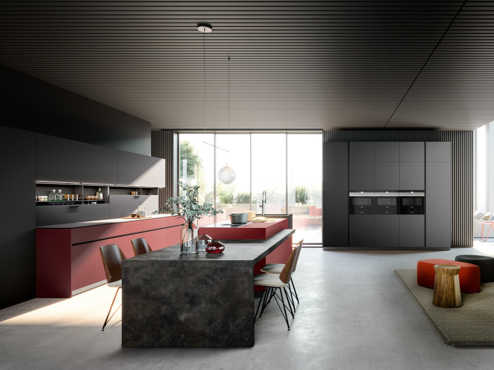 На фото: кухня в стиле модернизм с обеденным столом, монолитной мойкой, плоскими фасадами, красными фасадами, техникой под мебельный фасад, островом и красной столешницей