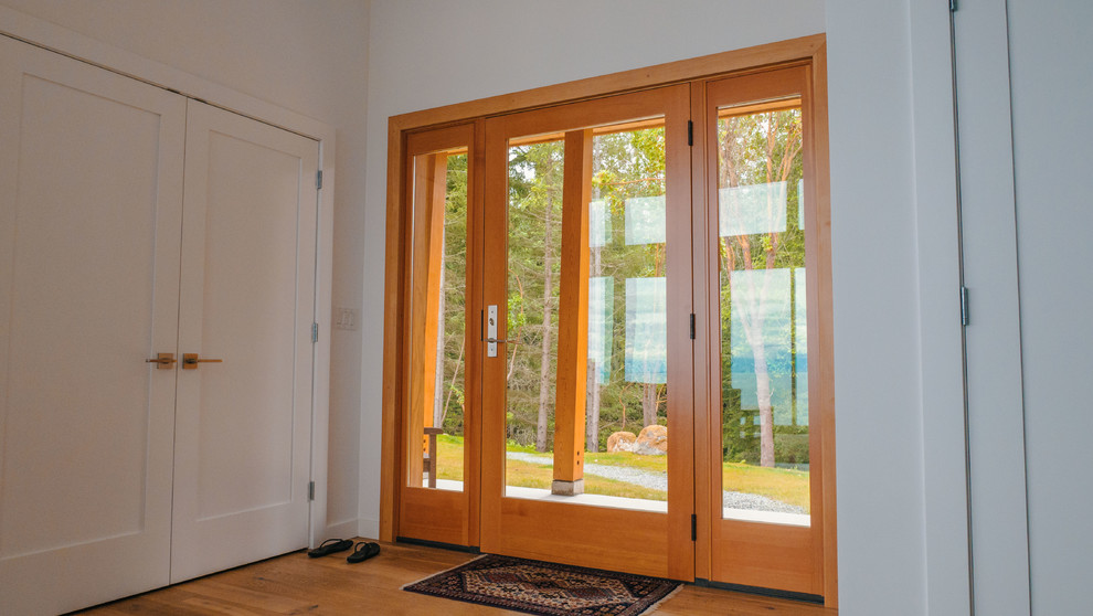 This is an example of a mid-sized front door in Vancouver with white walls, medium hardwood floors, a single front door and a medium wood front door.