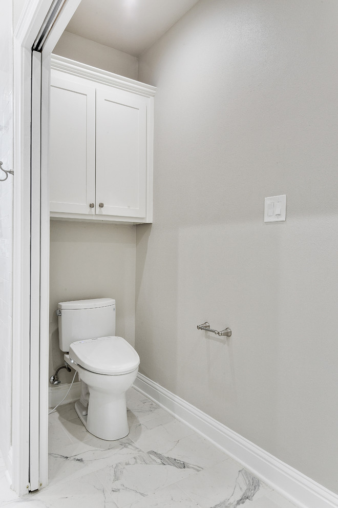 Photo of a large traditional powder room in New Orleans with shaker cabinets, white cabinets, a two-piece toilet, white tile, subway tile, grey walls, porcelain floors, an undermount sink, quartzite benchtops, multi-coloured floor and white benchtops.