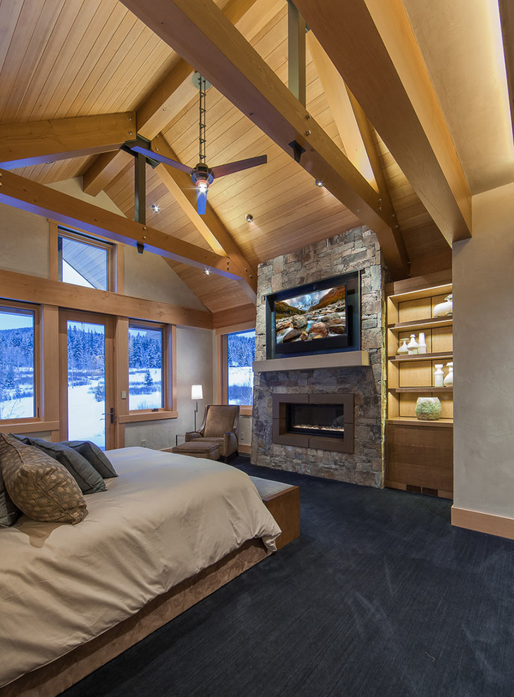 Photo of a large contemporary master bedroom in Denver with beige walls, carpet, a standard fireplace, a stone fireplace surround and blue floor.