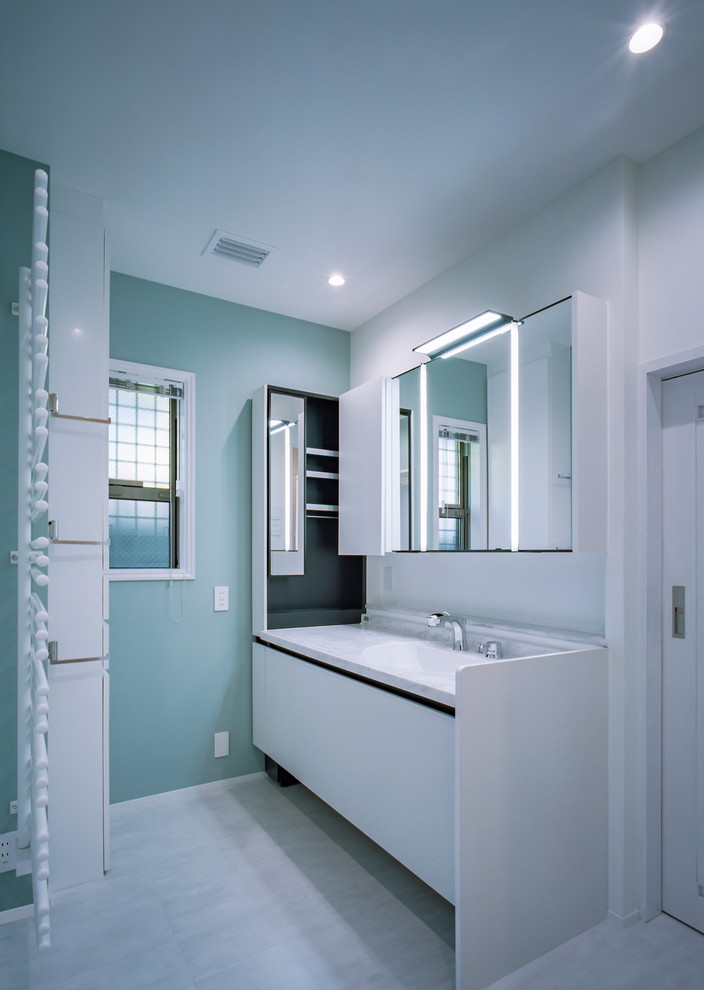 Design ideas for a mid-sized modern powder room in Kobe with beaded inset cabinets, white cabinets, green walls, vinyl floors, an undermount sink, solid surface benchtops, beige floor and white benchtops.