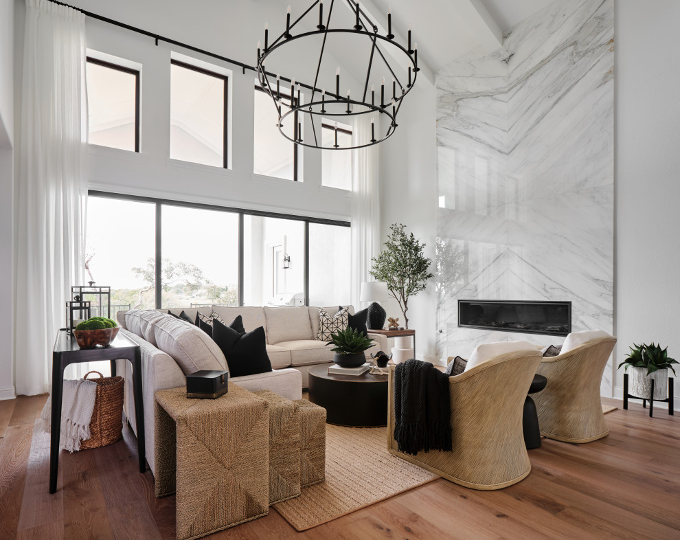 Inspiration for a large transitional open concept living room in Austin with white walls, light hardwood floors, a standard fireplace, a stone fireplace surround, grey floor and vaulted.