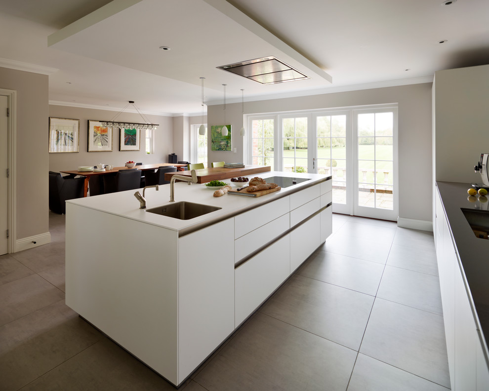 Large contemporary l-shaped eat-in kitchen in Surrey with an integrated sink, flat-panel cabinets, white cabinets, quartz benchtops, white splashback, glass sheet splashback, stainless steel appliances, ceramic floors and with island.