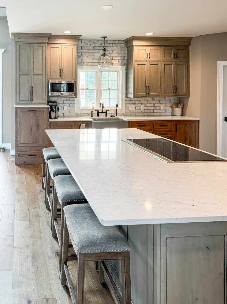 Large transitional l-shaped light wood floor eat-in kitchen photo with a farmhouse sink, beaded inset cabinets, quartz countertops, white backsplash, subway tile backsplash, stainless steel appliances and an island