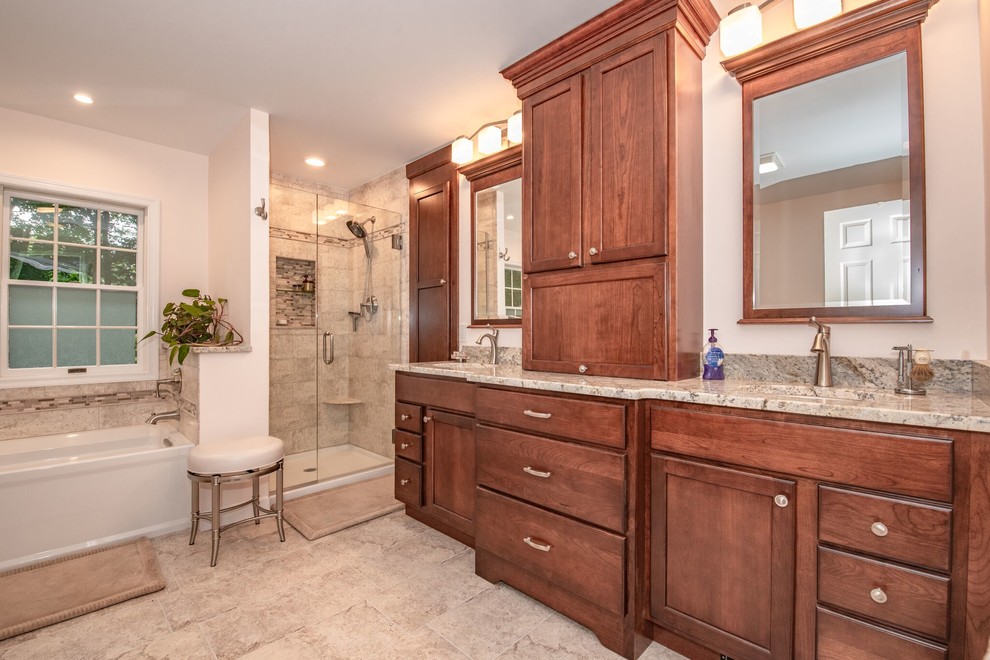 Photo of a large traditional master bathroom in New York with shaker cabinets, medium wood cabinets, a drop-in tub, an alcove shower, a two-piece toilet, beige tile, stone tile, beige walls, ceramic floors, a drop-in sink, laminate benchtops, beige floor, a hinged shower door and beige benchtops.