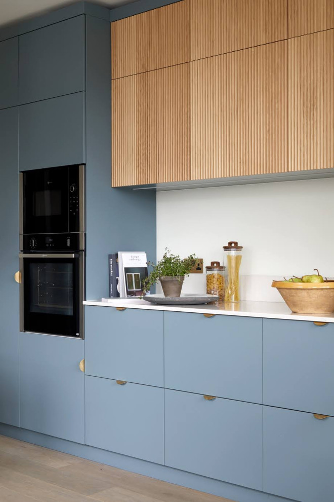 Immagine di una cucina moderna di medie dimensioni con ante in legno chiaro, top in superficie solida, paraspruzzi beige, elettrodomestici in acciaio inossidabile, pavimento beige e top bianco