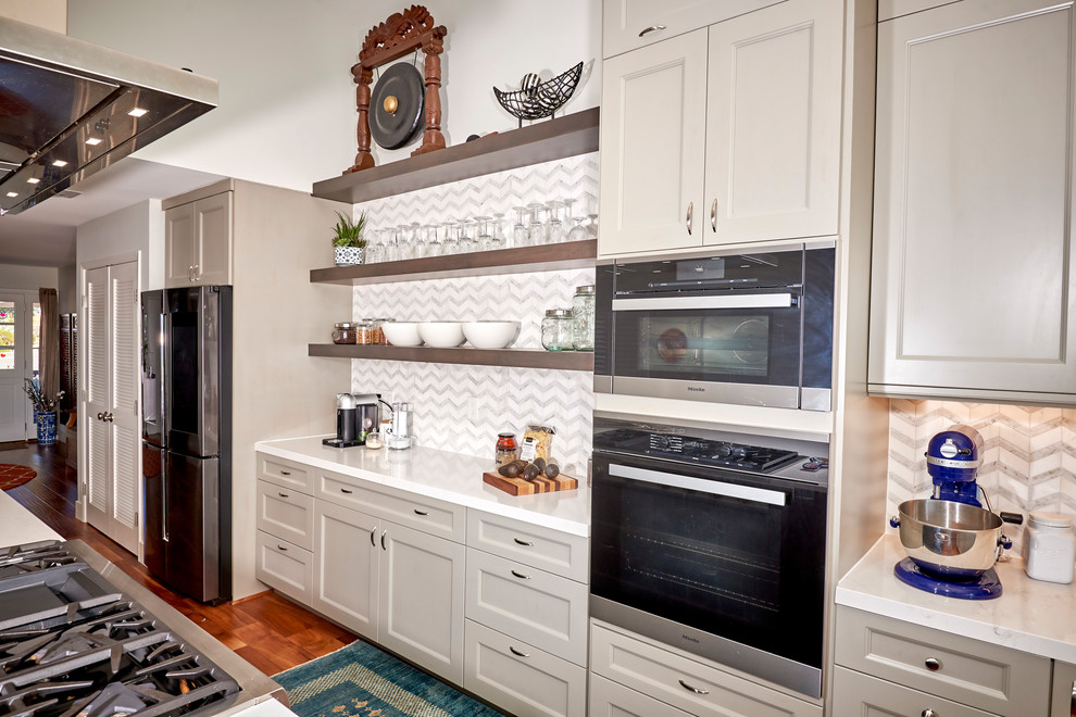 Large transitional l-shaped medium tone wood floor and brown floor open concept kitchen photo in Denver with an undermount sink, recessed-panel cabinets, gray cabinets, quartz countertops, white backsplash, marble backsplash, stainless steel appliances, an island and white countertops