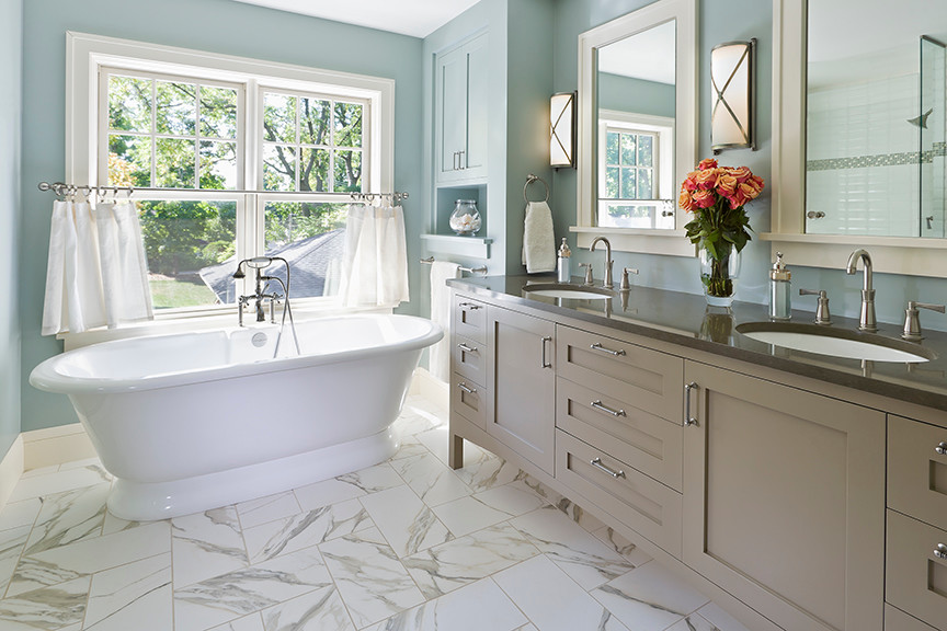 Inspiration for a large traditional bathroom in Minneapolis with shaker cabinets, brown cabinets, a freestanding tub, blue walls, marble floors, an undermount sink and solid surface benchtops.