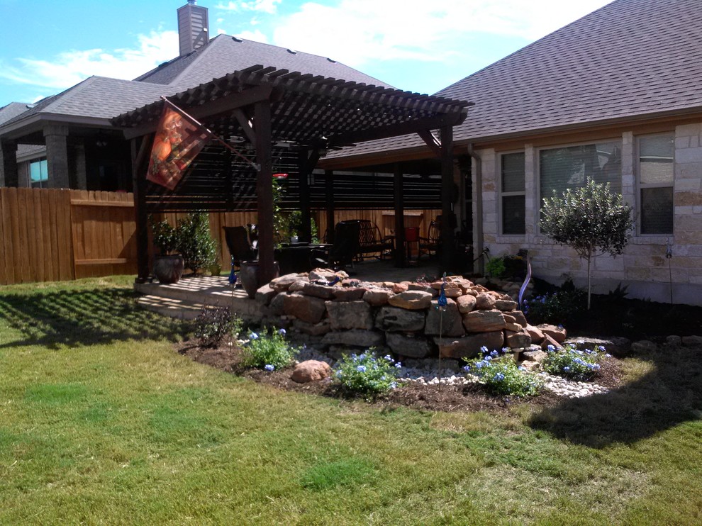 This is an example of a mid-sized traditional backyard patio in Austin with a fire feature, natural stone pavers and a pergola.