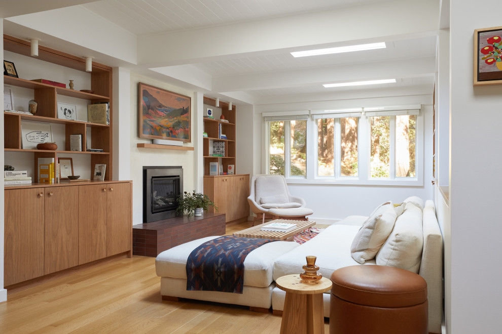 Mid-sized 1960s open concept light wood floor, brown floor and exposed beam living room photo in San Francisco with a bar, white walls, a standard fireplace, a plaster fireplace and a wall-mounted tv