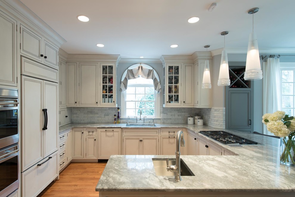 Inspiration for a large transitional u-shaped medium tone wood floor eat-in kitchen remodel with an undermount sink, beaded inset cabinets, white cabinets, marble countertops, white backsplash, marble backsplash, paneled appliances and a peninsula