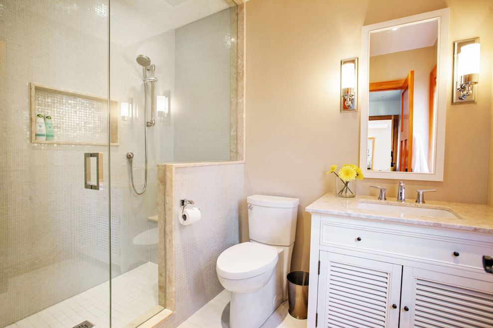 Photo of a small beach style 3/4 bathroom in Toronto with an undermount sink, louvered cabinets, white cabinets, marble benchtops, an alcove shower, a two-piece toilet, beige tile, porcelain tile, beige walls and porcelain floors.