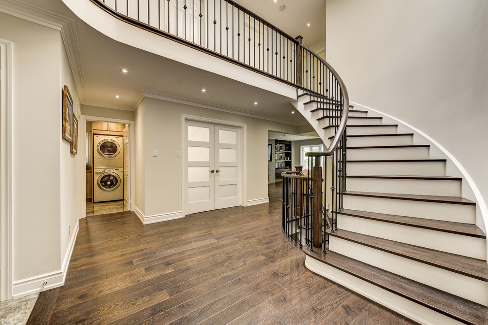This is an example of a large traditional wood spiral staircase in Toronto with painted wood risers and mixed railing.