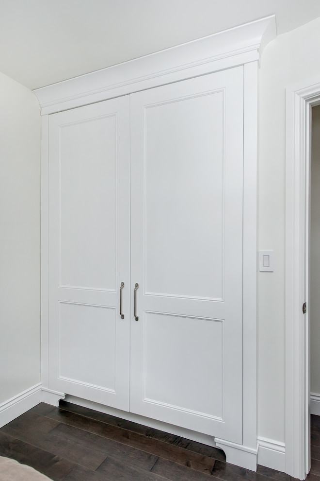 Inspiration for a mid-sized transitional gender-neutral dark wood floor reach-in closet remodel in Edmonton with recessed-panel cabinets and white cabinets
