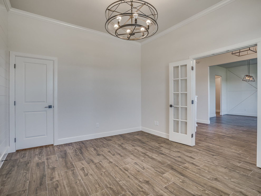 Photo of a large country home office in Oklahoma City with grey walls and light hardwood floors.