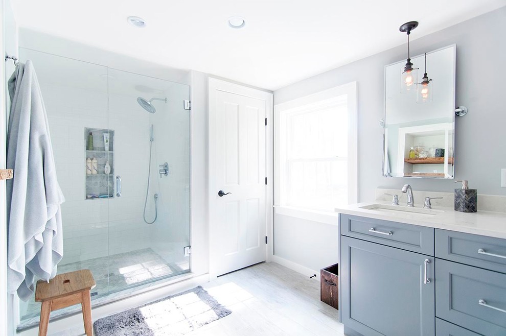 Alcove shower - large transitional master white tile and subway tile ceramic tile and gray floor alcove shower idea in Boston with recessed-panel cabinets, blue cabinets, gray walls, an undermount sink, laminate countertops and a hinged shower door