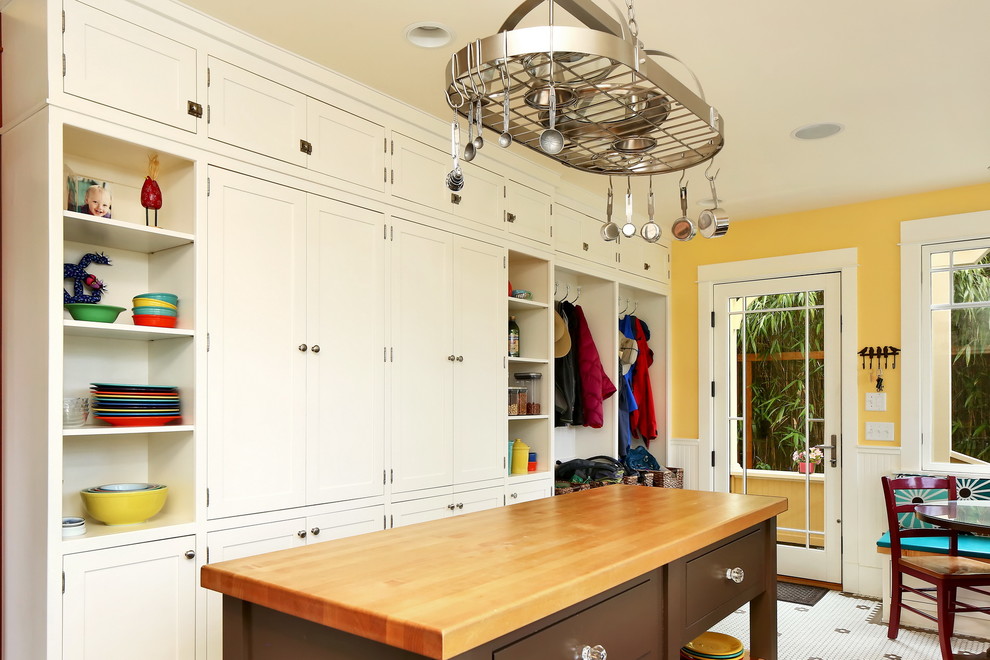 This is an example of a mid-sized traditional galley separate kitchen in Seattle with a farmhouse sink, shaker cabinets, white cabinets, wood benchtops, white splashback, subway tile splashback, stainless steel appliances, ceramic floors, with island, multi-coloured floor and brown benchtop.