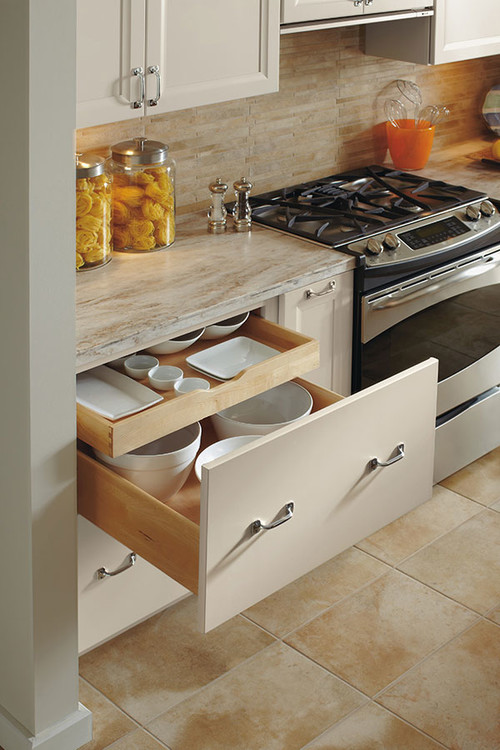 Deep drawer storage system with an internal roll-out tray organizing plates and bowls beside the stove