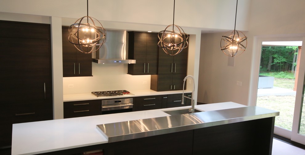 Mid-sized modern single-wall open plan kitchen in Chicago with an undermount sink, flat-panel cabinets, dark wood cabinets, quartz benchtops, panelled appliances, with island and white benchtop.