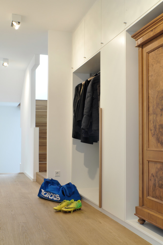 Contemporary mudroom in Munich with white walls and light hardwood floors.