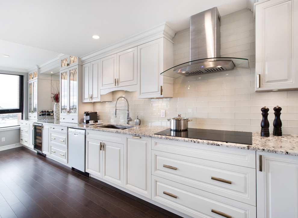 Inspiration for a large traditional l-shaped eat-in kitchen in Ottawa with an undermount sink, raised-panel cabinets, white cabinets, granite benchtops, white splashback, subway tile splashback, stainless steel appliances, dark hardwood floors, a peninsula and brown floor.