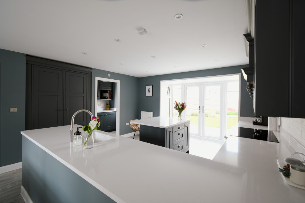 This is an example of a large traditional l-shaped eat-in kitchen in Essex with a single-bowl sink, shaker cabinets, grey cabinets, quartzite benchtops, black appliances, with island and white benchtop.