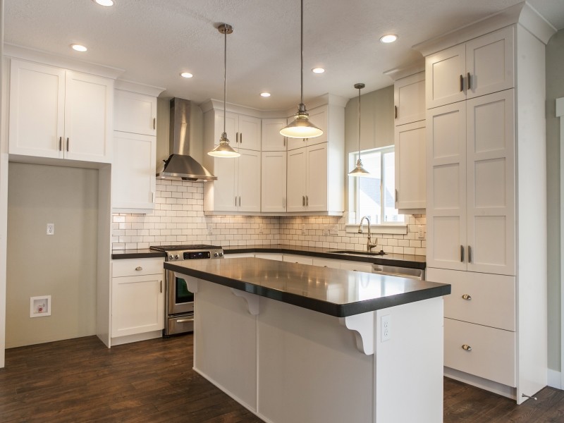 Design ideas for a large arts and crafts l-shaped eat-in kitchen in Salt Lake City with a drop-in sink, recessed-panel cabinets, white cabinets, quartzite benchtops, yellow splashback, subway tile splashback, stainless steel appliances, medium hardwood floors and with island.