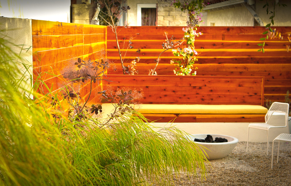This is an example of a small contemporary backyard partial sun garden in Los Angeles with a fire feature and gravel.