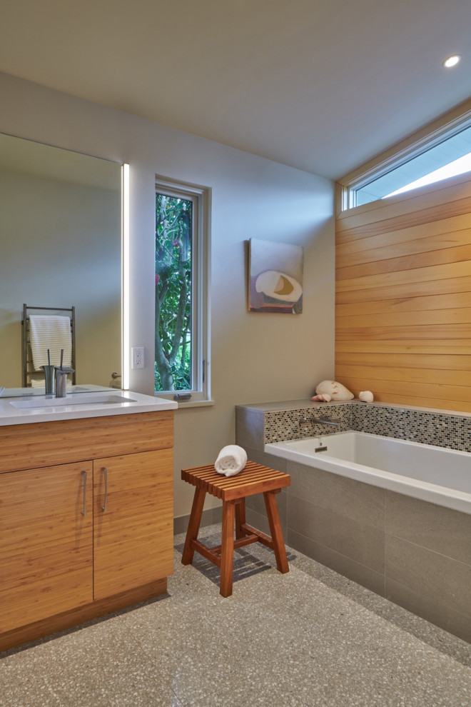 Photo of a mid-sized midcentury master wet room bathroom in Seattle with flat-panel cabinets, brown cabinets, a drop-in tub, a bidet, cement tile, white walls, terrazzo floors, an undermount sink, quartzite benchtops, grey floor, a hinged shower door, white benchtops, a single vanity, a freestanding vanity and vaulted.