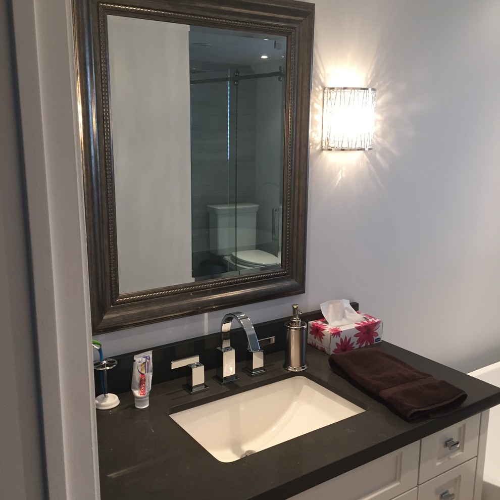 Inspiration for a mid-sized contemporary 3/4 bathroom in Toronto with shaker cabinets, white cabinets, a freestanding tub, a corner shower, a two-piece toilet, gray tile, ceramic tile, grey walls, ceramic floors, an undermount sink, granite benchtops, grey floor and a hinged shower door.