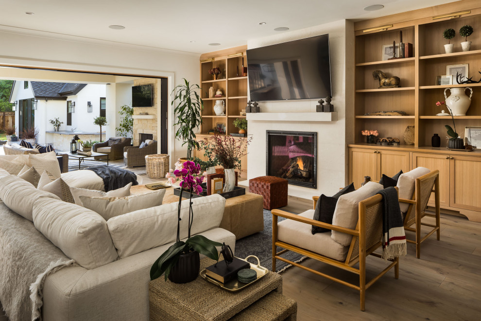 Design ideas for a large transitional open concept family room in San Francisco with a home bar, white walls, medium hardwood floors, a standard fireplace, a stone fireplace surround, a wall-mounted tv and grey floor.