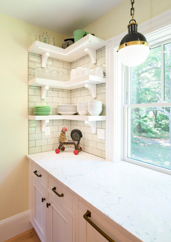This is an example of a mid-sized transitional l-shaped kitchen in Boston with a farmhouse sink, beaded inset cabinets, white cabinets, quartz benchtops, green splashback, ceramic splashback, stainless steel appliances, light hardwood floors, with island and white benchtop.