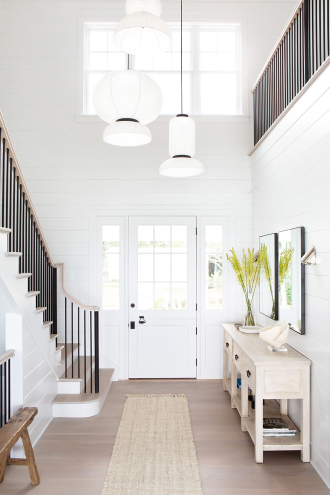 Mid-sized beach style front door in New York with white walls, light hardwood floors, a single front door, a white front door and beige floor.