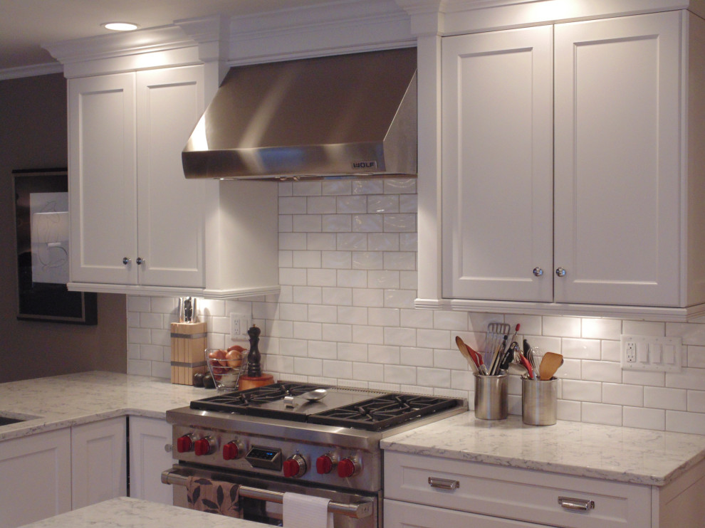 Large transitional u-shaped medium tone wood floor and brown floor eat-in kitchen photo with an undermount sink, recessed-panel cabinets, white cabinets, quartz countertops, white backsplash, subway tile backsplash, stainless steel appliances, an island and white countertops