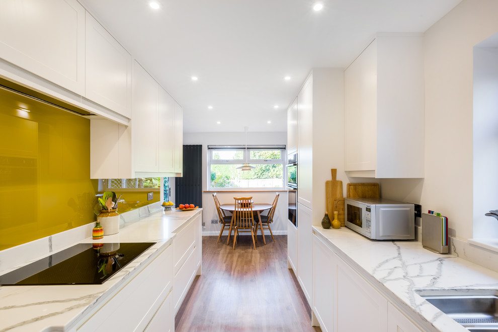 Contemporary galley eat-in kitchen in Surrey with white cabinets, quartzite benchtops, yellow splashback and white benchtop.