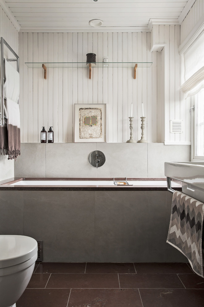 Mid-sized scandinavian bathroom in Stockholm with an undermount tub, gray tile, white walls and ceramic floors.