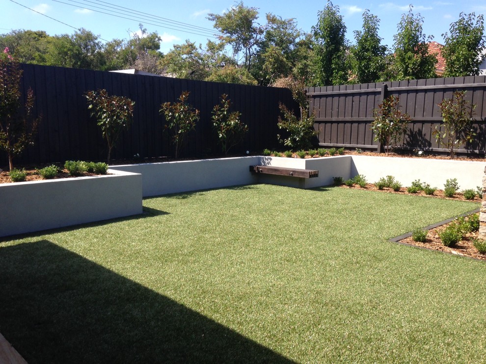 Design ideas for a mid-sized contemporary backyard full sun garden in Melbourne with a retaining wall and natural stone pavers.