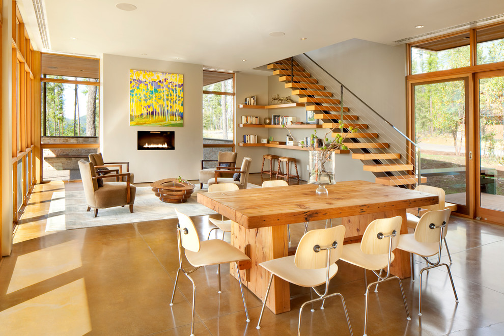 This is an example of a contemporary open plan dining in Other with concrete floors and a ribbon fireplace.