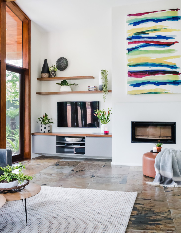 This is an example of a large midcentury open concept living room in Melbourne with white walls, slate floors, a wood stove, a plaster fireplace surround, a wall-mounted tv and brown floor.