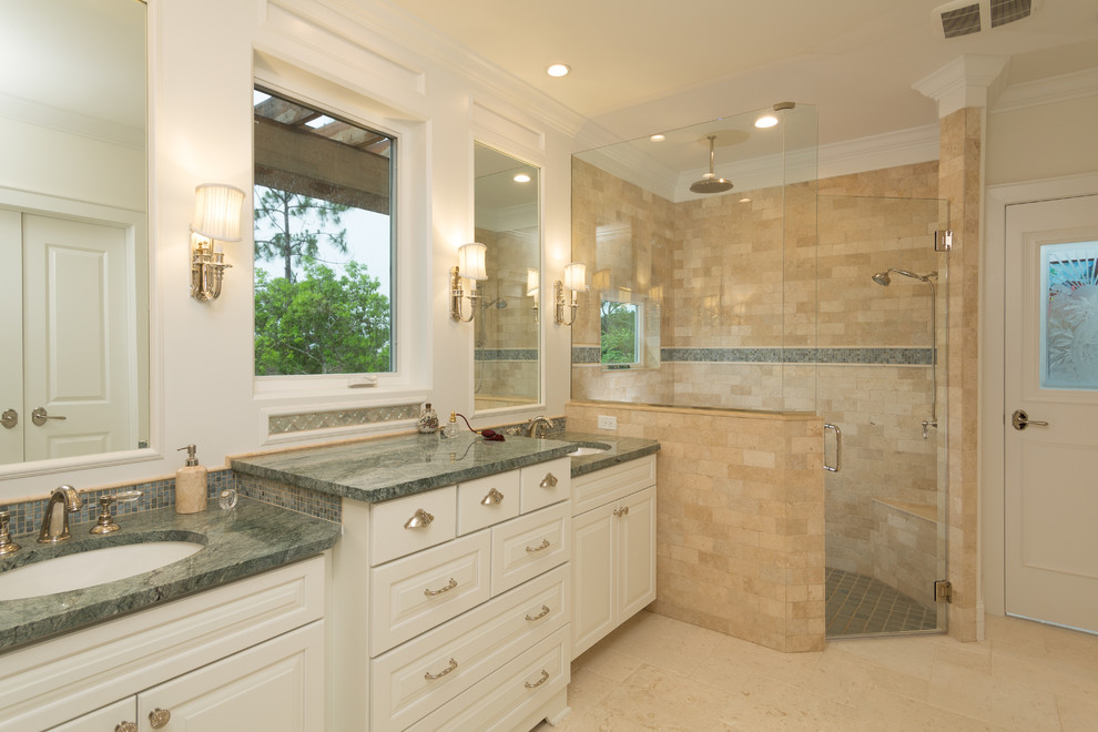 Large traditional master bathroom in Jacksonville with raised-panel cabinets, white cabinets, a corner shower, beige tile, porcelain tile, beige walls, travertine floors, an undermount sink, quartzite benchtops, beige floor, a hinged shower door and green benchtops.