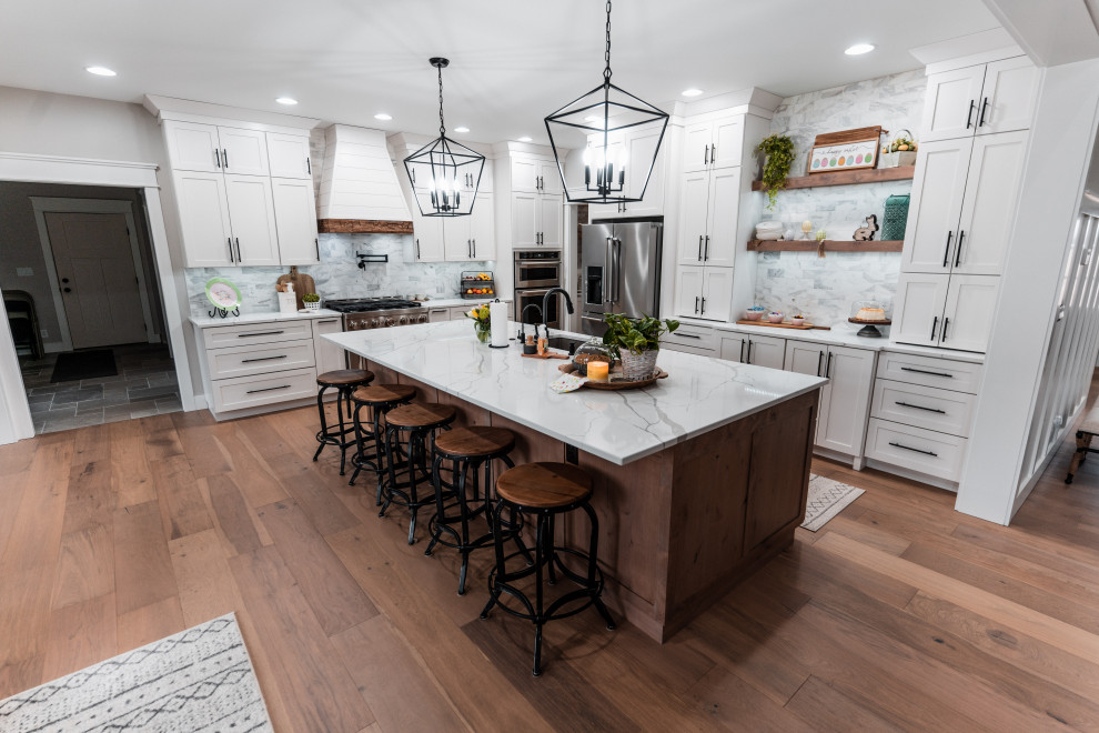 Example of a large cottage l-shaped light wood floor open concept kitchen design in Other with an undermount sink, shaker cabinets, white cabinets, quartz countertops, multicolored backsplash, marble backsplash, stainless steel appliances, an island and white countertops