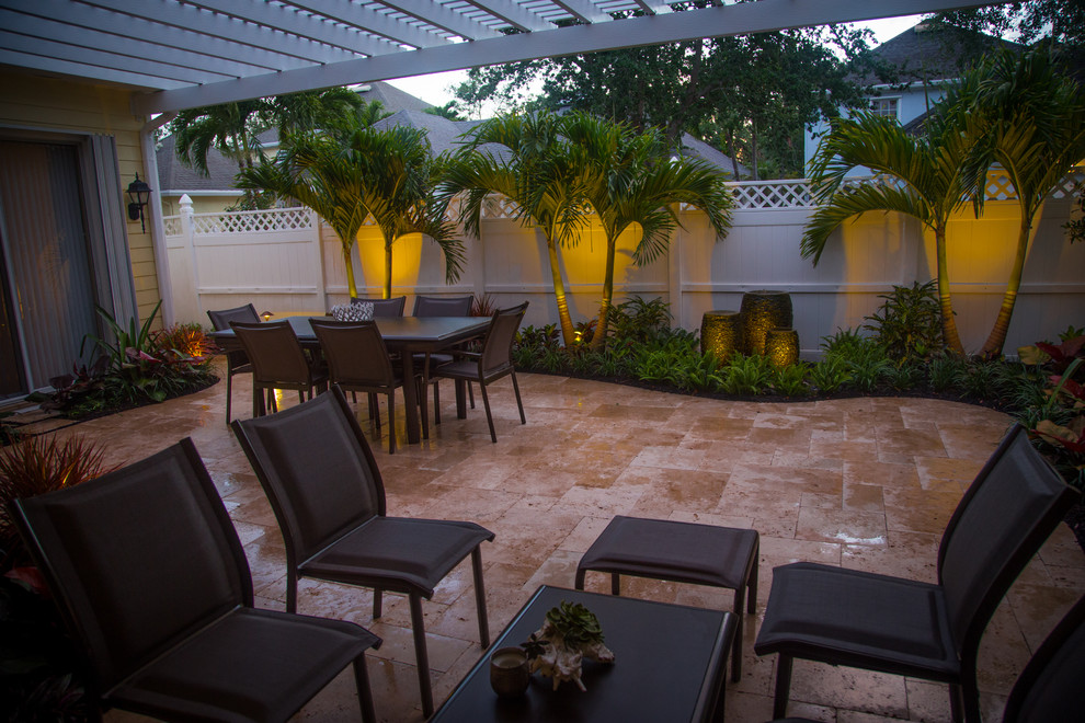 Small tropical courtyard patio in Miami with a water feature, natural stone pavers and a pergola.