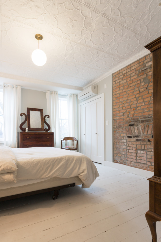 На фото: хозяйская спальня среднего размера в стиле кантри с синими стенами, деревянным полом, белым полом и кирпичными стенами без камина с
