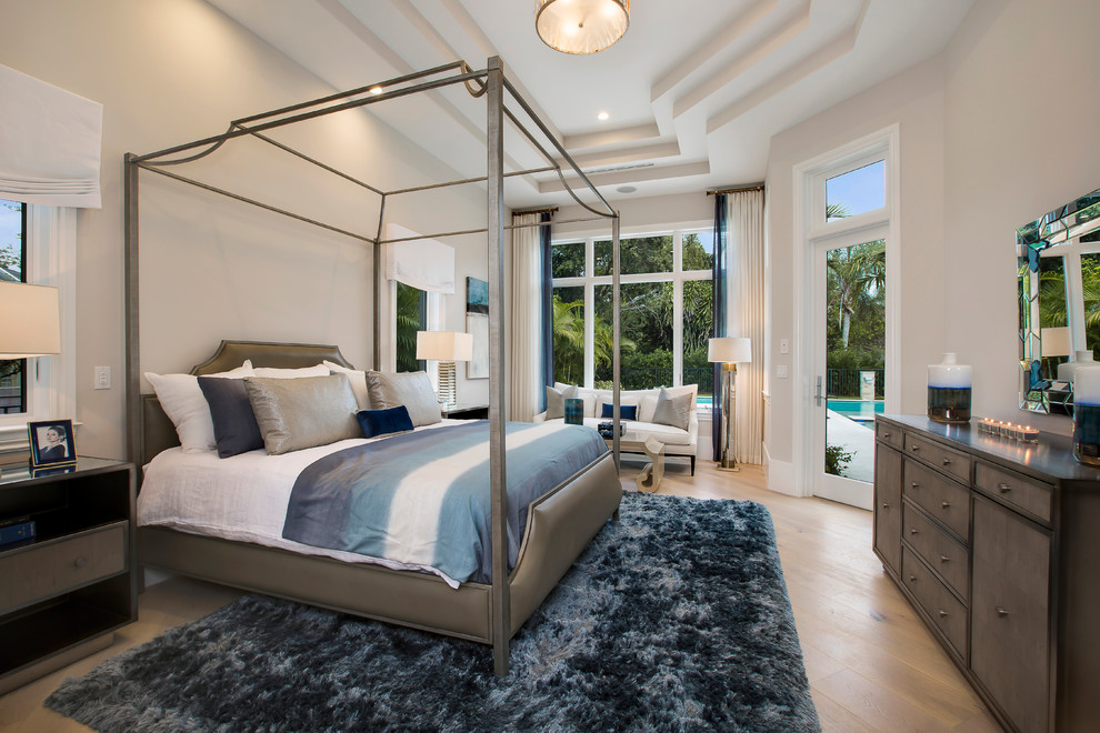 Photo of a large tropical bedroom in Tampa with beige walls and medium hardwood floors.